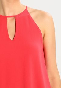 Pink top ilman hihnoja, jossa on avainreikänäyttö. Valmistettu kevyestä kankaasta, jossa on sileä pinta ja minimaalinen ompelu.