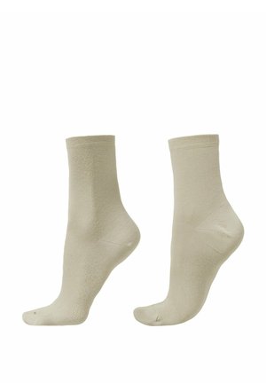 Paire de chaussettes beige jusqu'à la cheville présentées verticalement sur un fond blanc uni, mettant en valeur leur forme et texture.