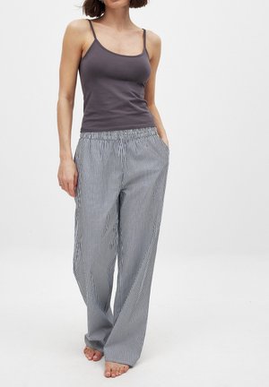Sivý top bez rukávov a pruhované široké nohavice s elastickým pásom; nohavice majú tenké vertikálne pruhy v modrej a bielej farbe.