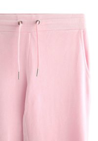 Różowe spodnie dresowe z polaru z regulowanym paskiem w talii zakończonym srebrnymi metalowymi zakończeniami, kieszeniami po bokach oraz miękką, gładką fakturą.