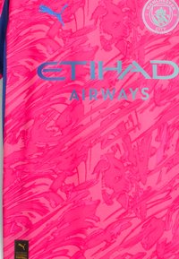 Puma fotbollsjacka i stark rosa med abstrakt mönster, med "ETIHAD AIRWAYS" i blått och Manchester City:s sköld, strukturerad tyg.