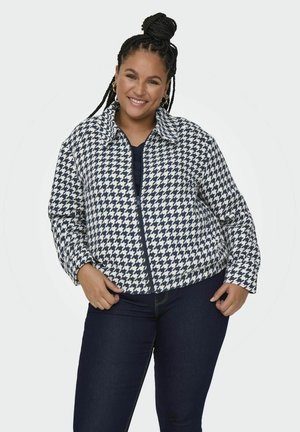 Marynarka w wzór houndstooth w granatowo-białym kolorze, z kołnierzykiem, zamek błyskawiczny i luźny fason, w połączeniu z ciemnymi dżinsami.