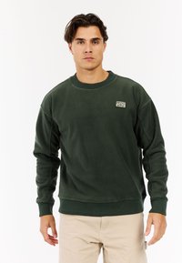 Donkergroene fleece sweatshirt met een geribde ronde hals en boorden, voorzien van een klein logo-label op de linkerborst. Gladde textuur.
