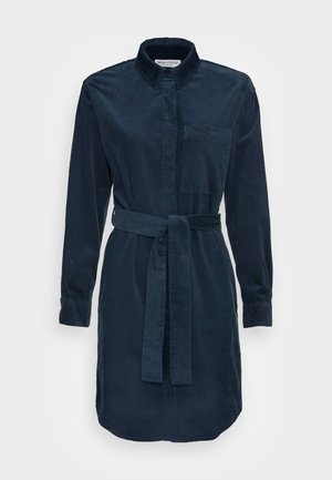 Námořnické kordové šaty s límečkem, dlouhými rukávy a odpovídajícím páskem. Má náprsní kapsu a mírně zakřivený lem.