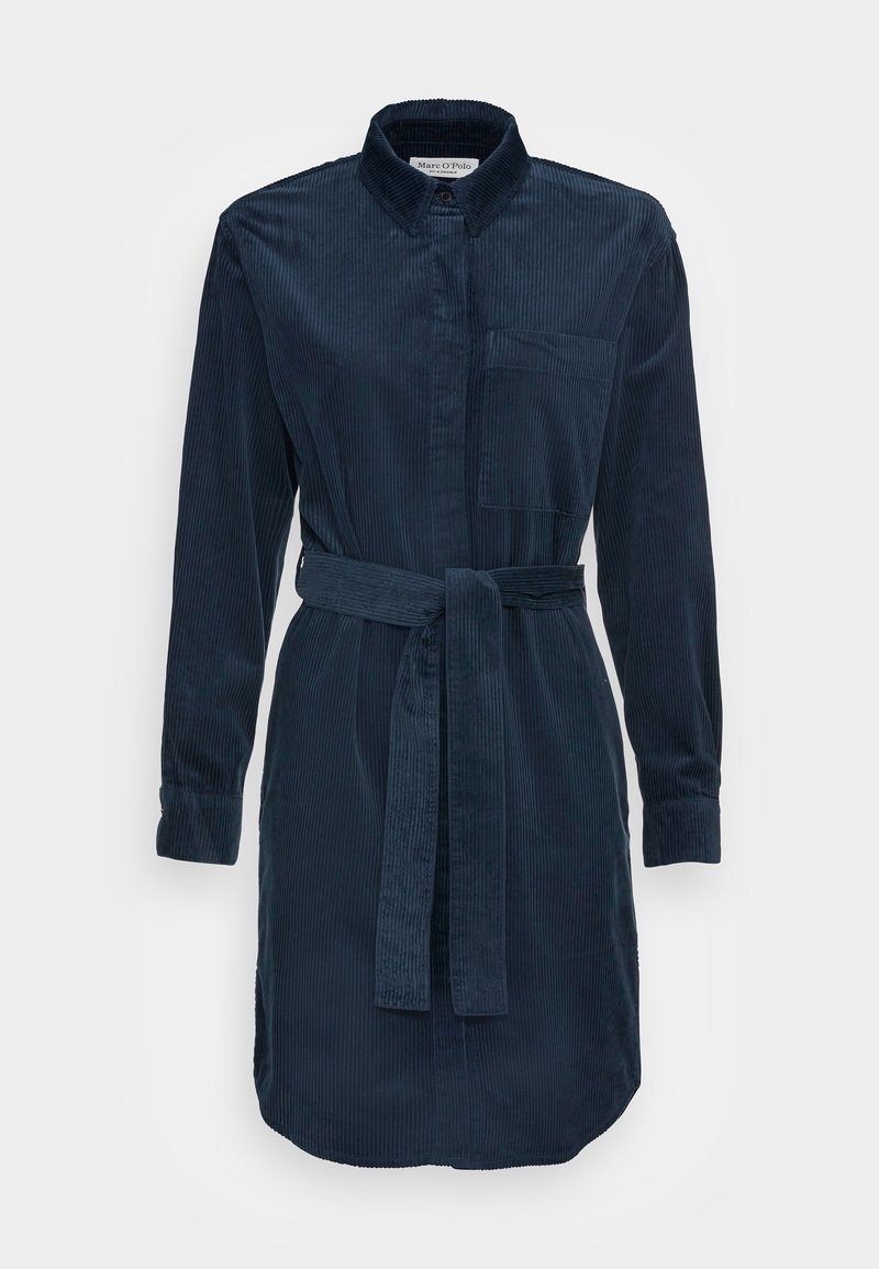 Laivaston sininen corduroykangasta valmistettu paitamekko, jossa on kaulus, pitkät hihat ja yhteensopiva vyö. Varustettu rintataskulla ja hieman kaarevalla helman muotoilulla.