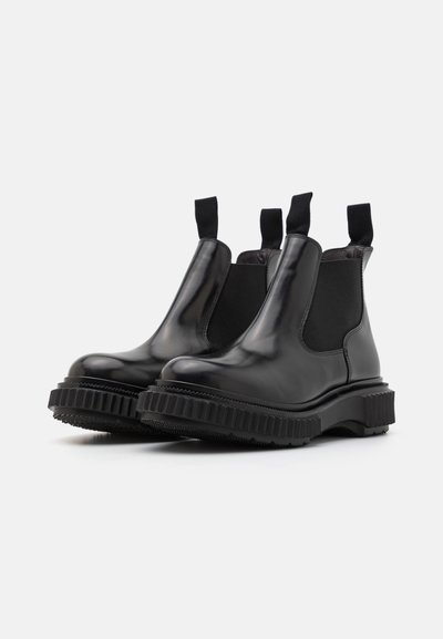 Botas de tobillo Chelsea de cuero negro con paneles laterales elásticos, lengüetas y suelas de goma gruesas con textura acanalada.