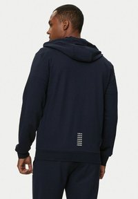 Felpa con cappuccio navy in morbido tessuto, caratterizzata da un design semplice, cappuccio regolabile e tre linee riflettenti sul retro vicino all'orlo.