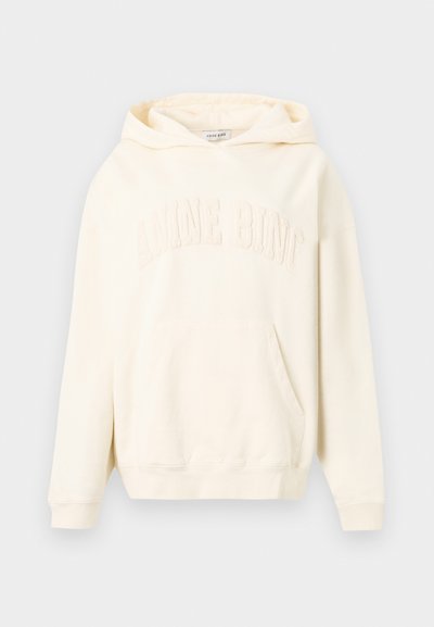 Sweat à capuche couleur crème avec poche kangourou et texte en relief "ANINE BING" sur la poitrine, présenté sur un fond uni.