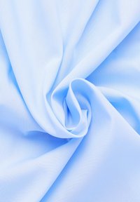 Tessuto azzurro chiaro con una consistenza liscia e morbida, che si adagia in una forma spirale, caratterizzato da una finitura uniforme e omogenea senza motivi.