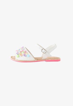 Weiße Sandalen mit einer weichen Wildleder-Innensohle, die mit bunten dekorativen Perlen an der Vorderseite versehen sind und eine pinkfarbene Gummisohle haben. Verstellbarer Knöchelriemen.