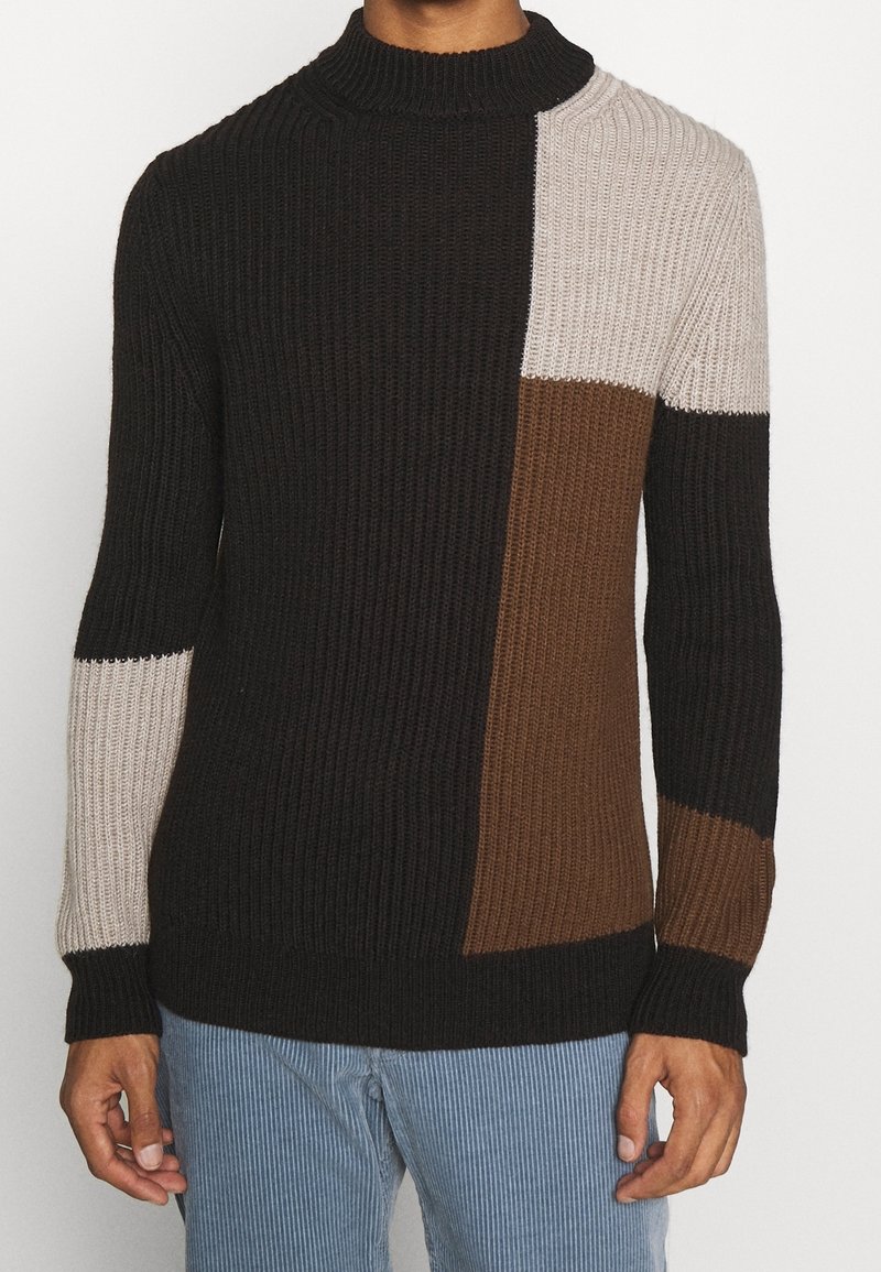 Stickad tröja med hög krage, prydd med block i svart, brunt och beige, ribbat mönster och åtsittande ärmslut.