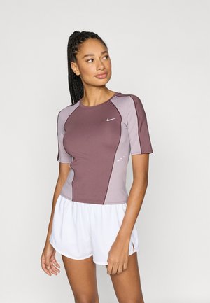 Krótki rękaw Nike w kolorze bordowym i jasnofioletowym, z okrągłym dekoltem, dopasowanym krojem i logo. Połączony z białymi szortami.