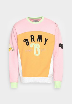 Sweatshirt à col rond avec des panneaux roses, oranges et gris. Présente un graphique de banane sur la manche et un texte brodé "GRMY jungle juice" en vert et noir.