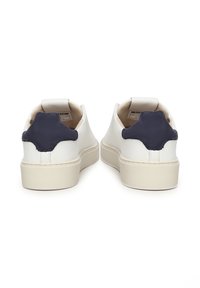 Zapatillas de cuero blanco con acentos de ante azul marino en el talón, forma redondeada, suela de goma beige y diseño minimalista. Forro interior suave.