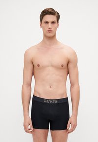 Svarta bomullskalsonger med ett grått elastiskt midjeband som har "Levi's"-logotypen. Åtsittande design med en slät, mjuk textur.