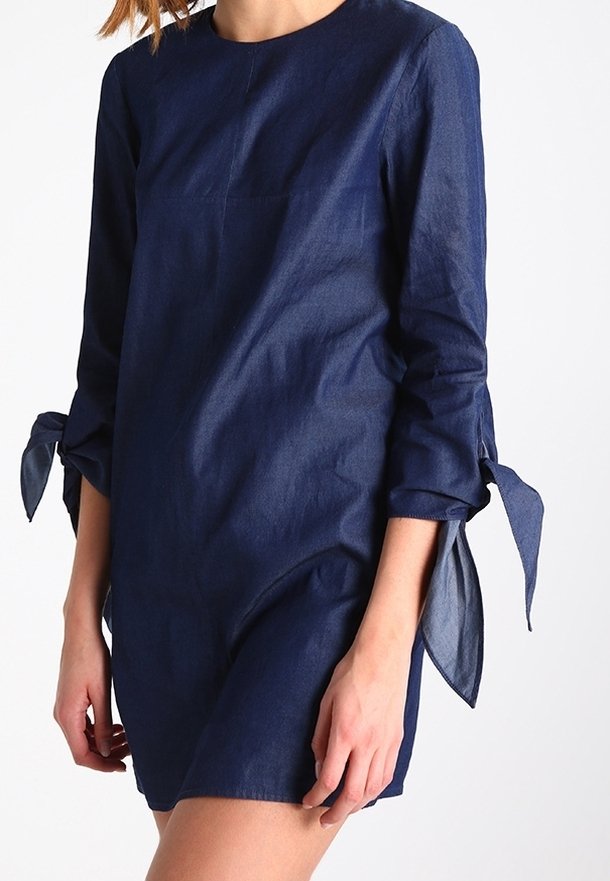 Laivasilmärtinen pellavamekko, jossa on pitkät hihat, sidottavat hihansuut ja pyöreä pääntie. Ominaisuuksiin kuuluu yksinkertainen, rento istuvuus ja minimalistinen muotoilu.