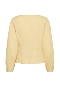 Blouse jaune clair à manches longues avec un décolleté carré, une taille cintrée et des poignets à boutons, vue de dos.