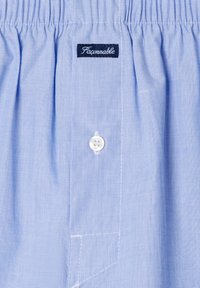 Boxer de algodón azul claro con cinturilla elástica, bragueta con un solo botón blanco y etiqueta negra con la palabra "Faconnable" en el centro delantero.