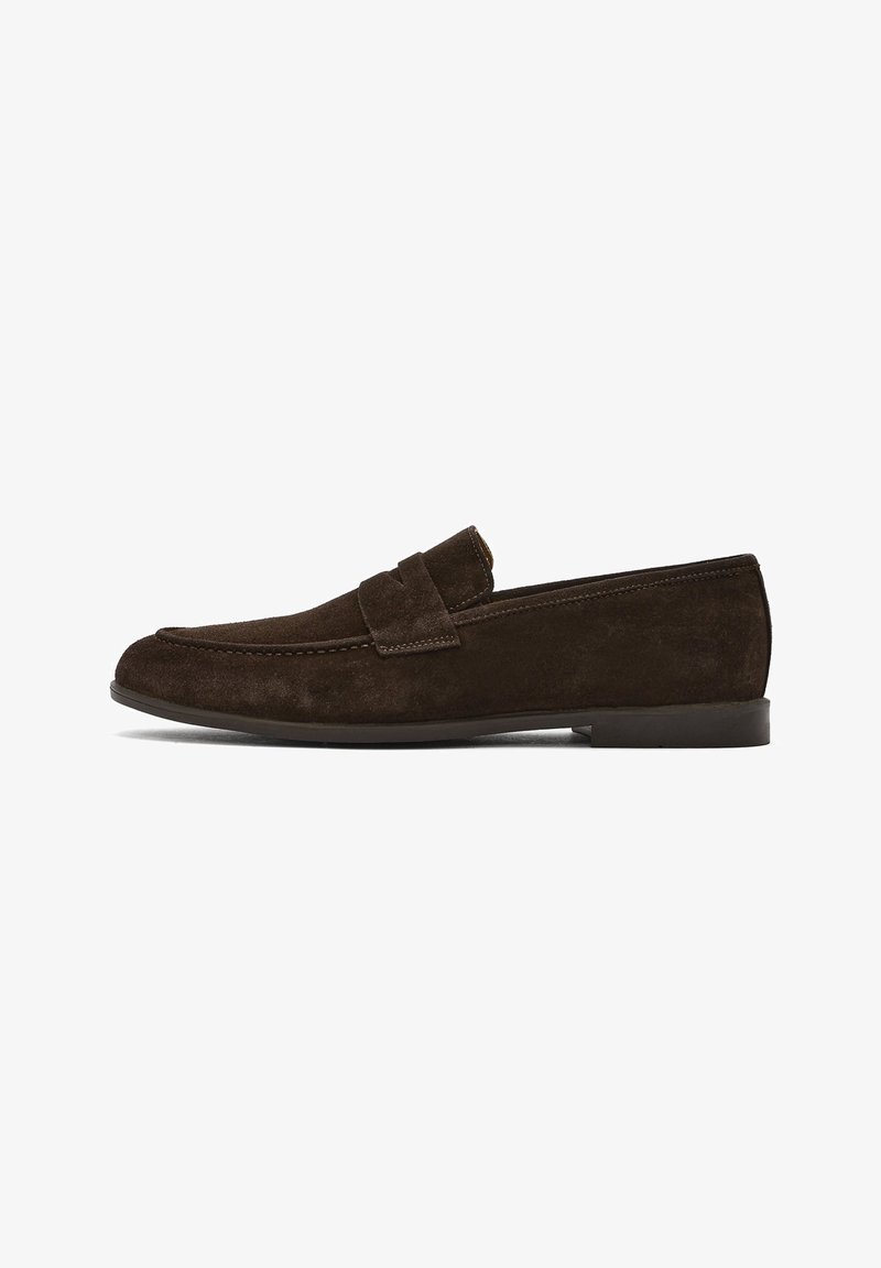 Brown suede loafers with a flat heel, featuring a stitched toe and a decorative strap across the vamp. Smooth texture and streamlined design.