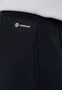 Shorts sportivi neri realizzati in un tessuto testurizzato, con una tasca laterale e un logo bianco "AEROREADY" sull'elastico in vita.