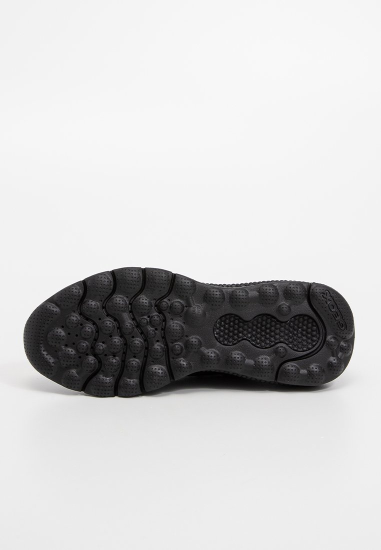 Sole di sneaker in gomma nera con un motivo di presa testurizzato, caratteristiche arrotondate e piccole indentazioni circolari per una migliore aderenza.