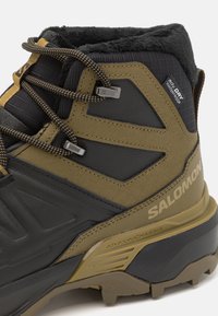 Czarno-oliwkowe buty trekkingowe wykonane z wodoszczelnego materiału, z teksturowanym materiałem, solidną podeszwą i odblaskowymi detalami.