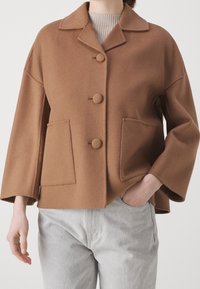 Chaqueta marrón de mezcla de lana con cuello, botones delanteros y dos bolsillos laterales. Presenta un ajuste holgado y mangas recortadas.