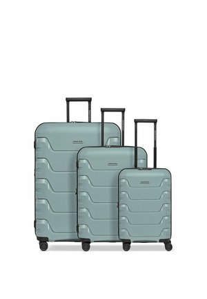 Tre valigie rigide color verde acqua di diverse dimensioni con manici telescopici neri e quattro ruote girevoli, disposte da sinistra a destra in ordine di grandezza.