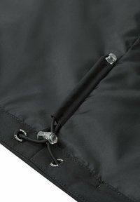 Tessuto nero con finitura opaca presenta una chiusura con coulisse dotata di fermagli in plastica trasparente e accenti di branding circolari.