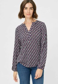 Langarmbluse mit einem geometrischen Muster in Marineblau, Pink und Creme. Sie hat einen V-Ausschnitt und Raffungen an den Manschetten für einen lässigen Schnitt.