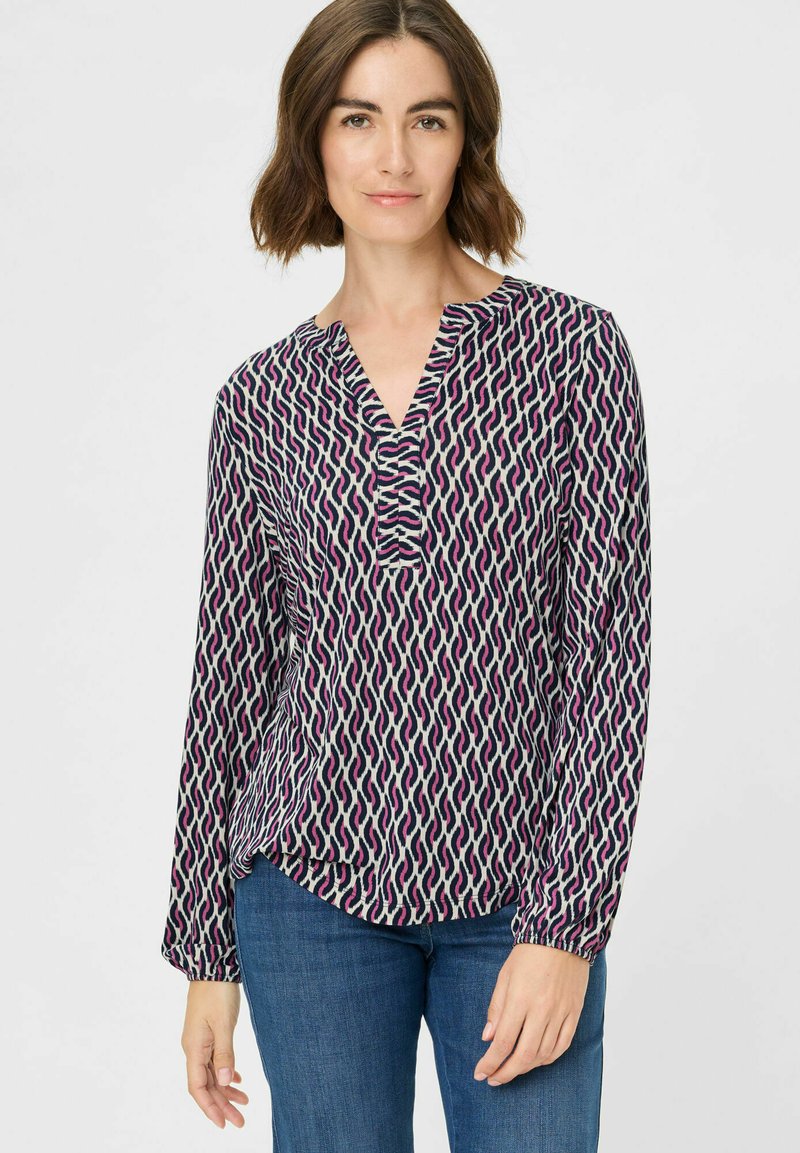 Langarmbluse mit einem geometrischen Muster in Marineblau, Pink und Creme. Sie hat einen V-Ausschnitt und Raffungen an den Manschetten für einen lässigen Schnitt.