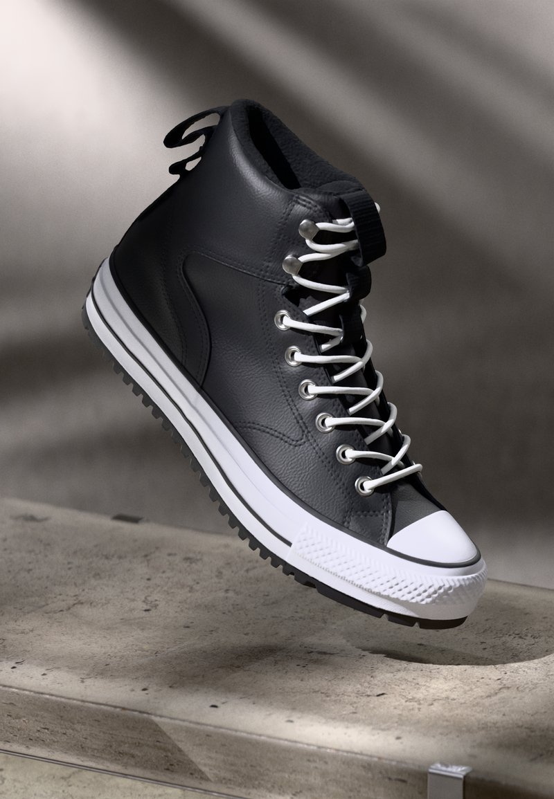 Schwarzer hoher Sneaker aus strukturiertem Leder, ausgestattet mit weißen Schnürsenkeln, einer weißen Gummikappe und einer geriffelten schwarzen Außensohle.