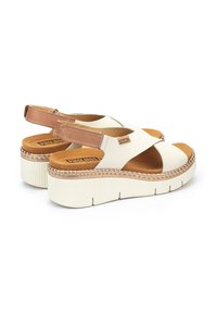 Sandalias de plataforma blancas y beige con correas cruzadas, suela texturada y acento de costura. Plantilla acolchada para mayor comodidad.