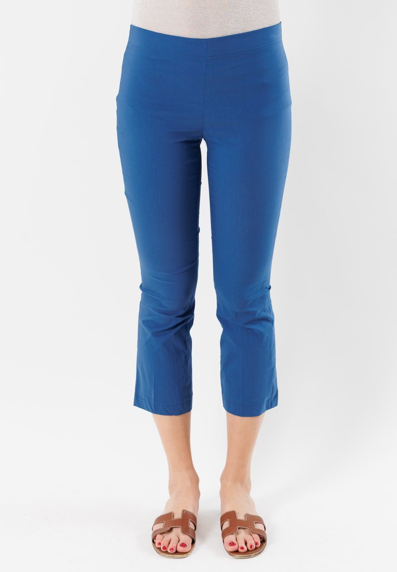 Pantaloni blu a vita alta con un design aderente e una cintura elastica, realizzati in materiale leggero, abbinati a sandali piatti marroni.