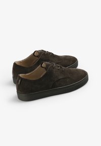 Zapatos de ante marrón con punta redonda, diseño de cordones y suela de goma negra. Presentan costuras mínimas y un forro interior suave.