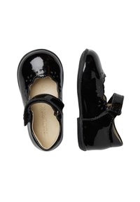 Zapatos de charol negros con punta redonda, bordes festoneados, una correa de velcro y detalles texturizados en la superficie superior.
