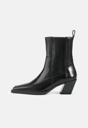 Black leather ankle boot with a pointed toe, ribbed side panels, and a block heel featuring a metallic accent. Smooth texture and sleek design.