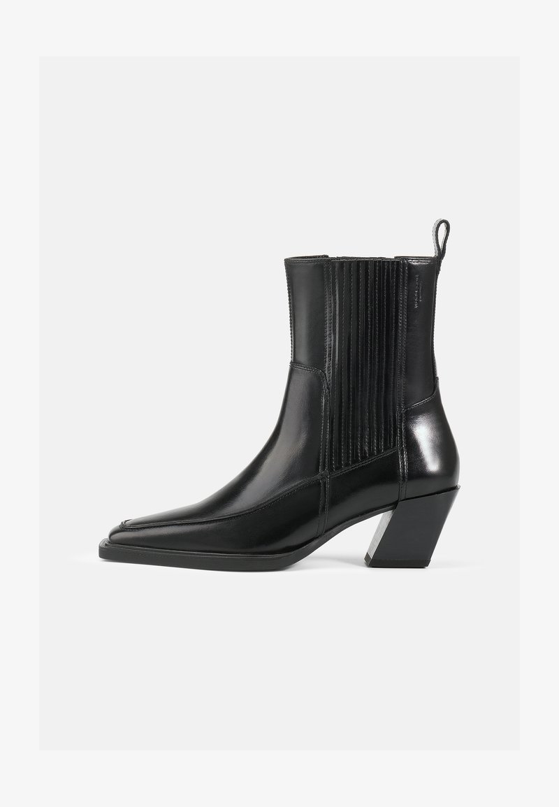 Bota de tornozelo em couro preto com bico apontado, painéis laterais em relevo e um salto bloco com um acréscimo metálico. Textura suave e design elegante.