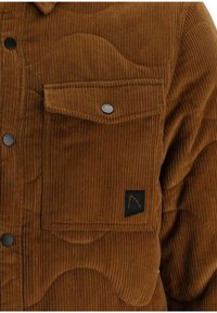 Veste en velours côtelé marron avec une poche à rabat boutonnée sur la poitrine et des boutons-pression noirs sur le devant.