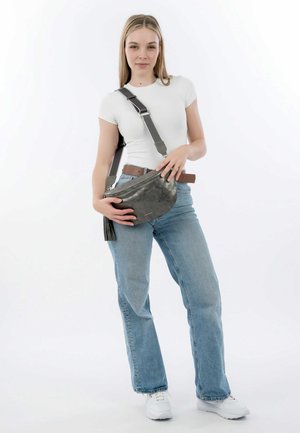 Grau Leder Umhängetasche mit Reißverschluss und Quastendetail, kombiniert mit hellblauen Jeans und einem taillierten weißen Hemd.