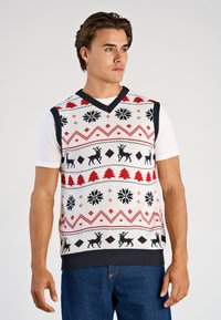 Gebreid mouwloos vest in wit met rode en zwarte kerstpatronen; met rendieren, sneeuwvlokken en bomen; marineblauwe bies en zoom.