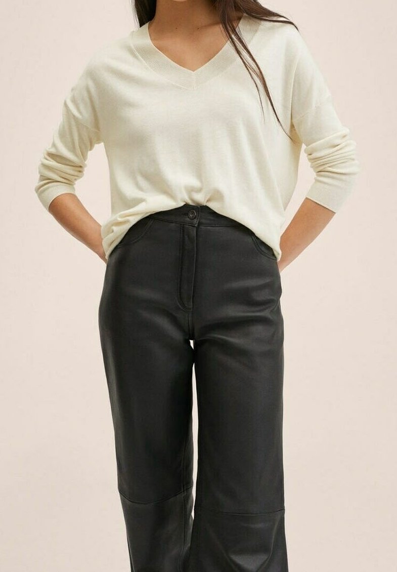 Pull en V créme fabriqué à partir d'un tissu doux, associé à un pantalon large en cuir noir taille haute avec fermeture à bouton et poches.