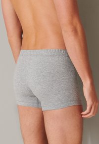 Grau melierte Baumwoll-Boxershorts mit einem elastischen Bund, die eine enge Passform und eine glatte Textur aufweisen, von hinten betrachtet.