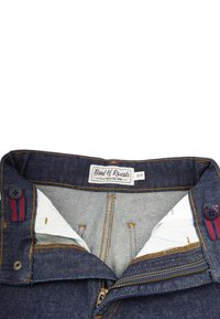 Denim jeans with a dark blue wash, featuring contrasting orange stitching, a zipper closure, and a white fabric lining with a tag.