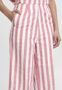 Striped wide-leg pants in light pink and white linen, featuring front pockets, a high waist, and a relaxed fit. Vertical stripes add visual interest.