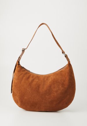 Sac à épaule en daim marron en forme de croissant avec une sangle réglable unique et une fermeture éclair sur le dessus sur fond neutre.