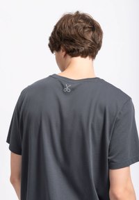 Grijze katoenen t-shirt met korte mouwen en een relaxte pasvorm. Heeft een schaar graphic geborduurd in lichtgroen op de achterkant van de hals.