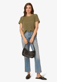 Olivově zelený pletený top s krátkým rukávem, v kombinaci s světle modrými džíny s rovnými nohavicemi. Černá kožená kabelka a černé mokasíny se zlatými detaily.