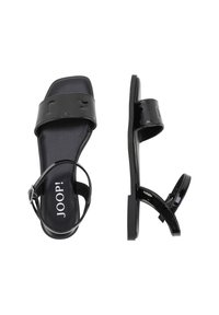 Sandali in pelle verniciata nera con una larga fascia anteriore e una cinghia alla caviglia, dotati di fibbia regolabile e suola piatta, design minimalista.