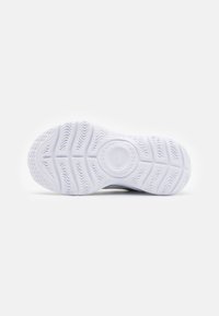 Semelle de chaussure en caoutchouc blanc avec un motif de semelle texturé, présentant un logo circulaire au centre et des rainures prononcées pour l'adhérence.